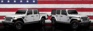 A 2023 Jeep Wrangler Unlimited and Jeep Gladiator standing in front of an American flag.